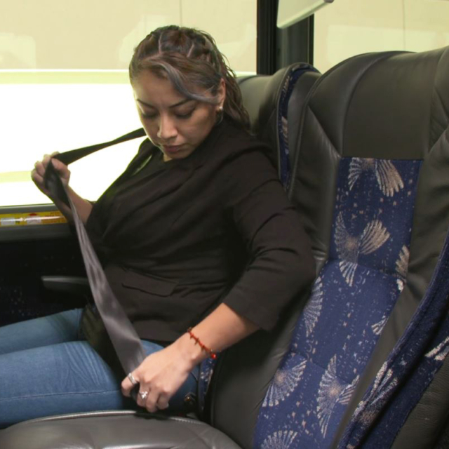 Lady buckling seat belt on bus ride
